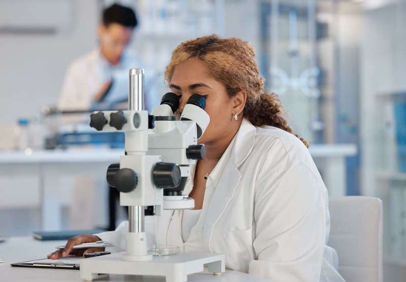 woman research scientist looking through microscope