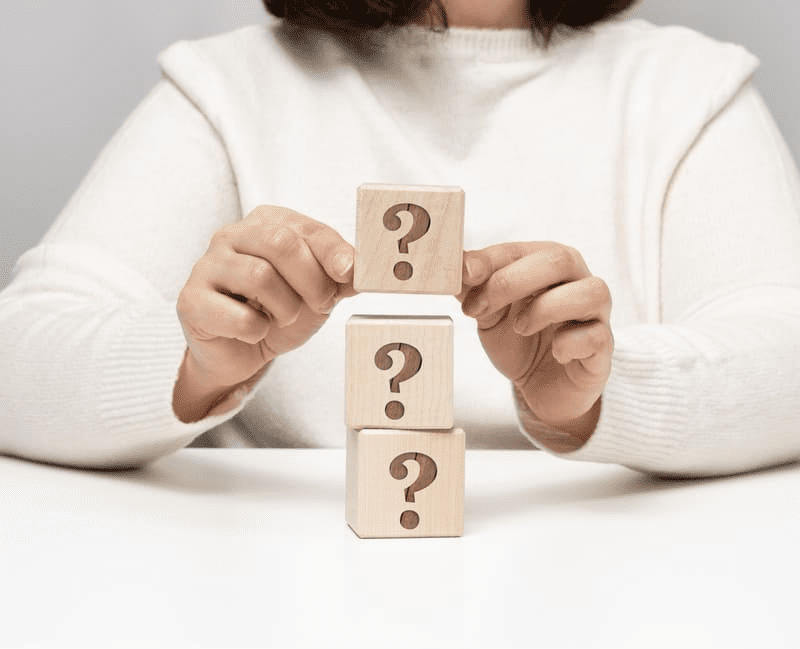 a person stacking wooden blocks with question marks